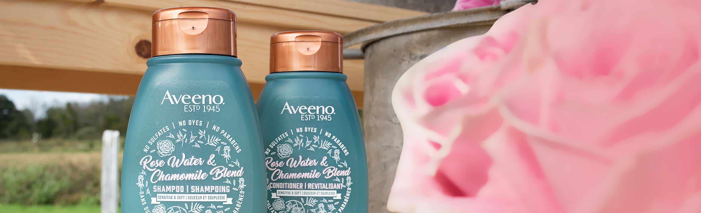 two bottles of aveeno products behind a rose