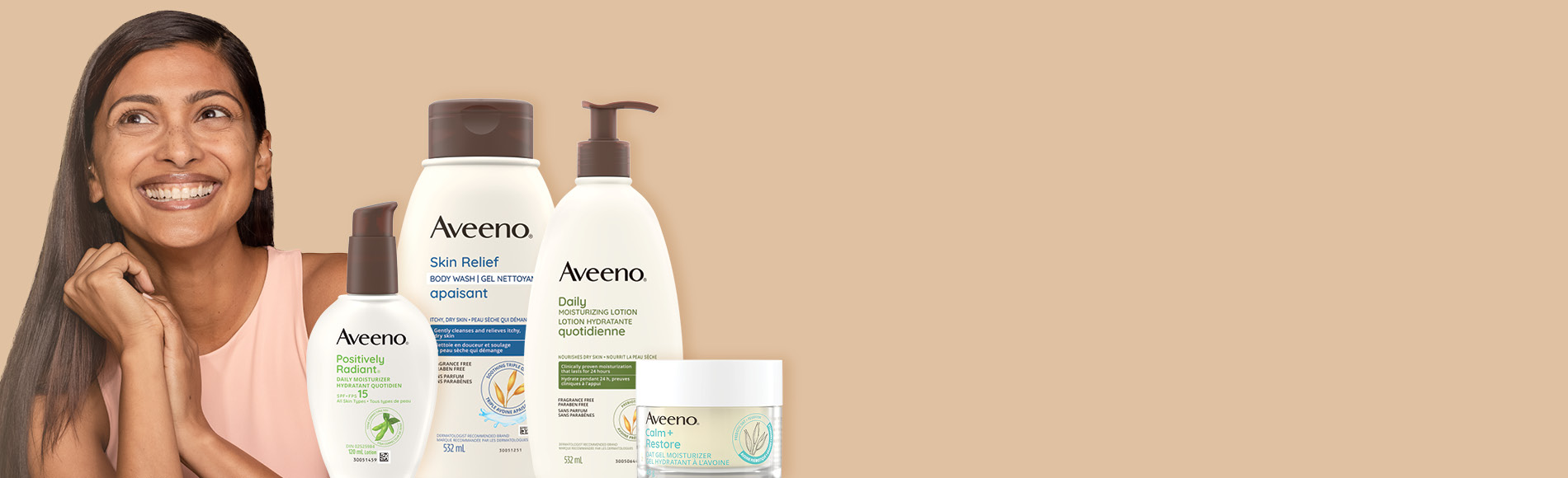 A banner with a woman with long dark straight hair smiling and four Aveeno® Body and Face Skincare products