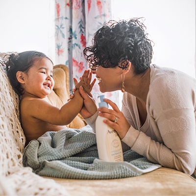 Happy mother and her baby using an AVEENO® BABY product