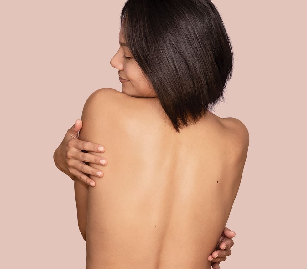 Woman's bare back against a pink backdrop