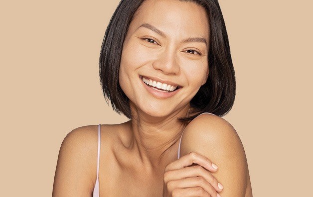 Woman with short dark hair holding her left arm and smiling