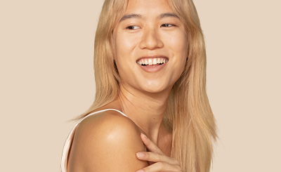 Woman with long blond hair looking over her left shoulder and smiling
