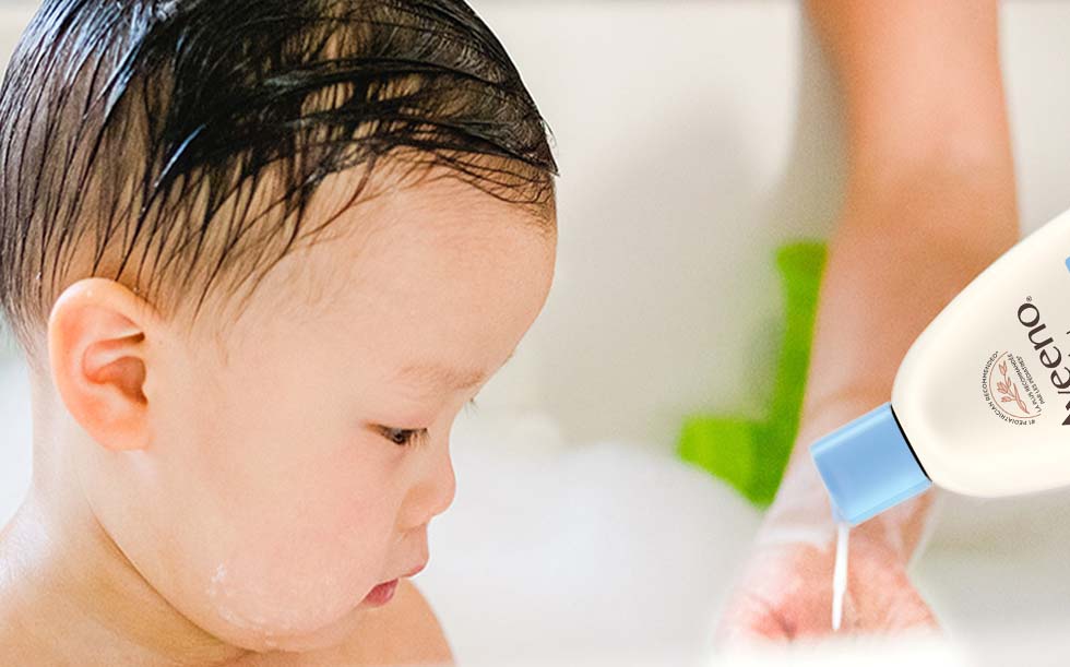 Mother washing her baby with AVEENO® BABY product