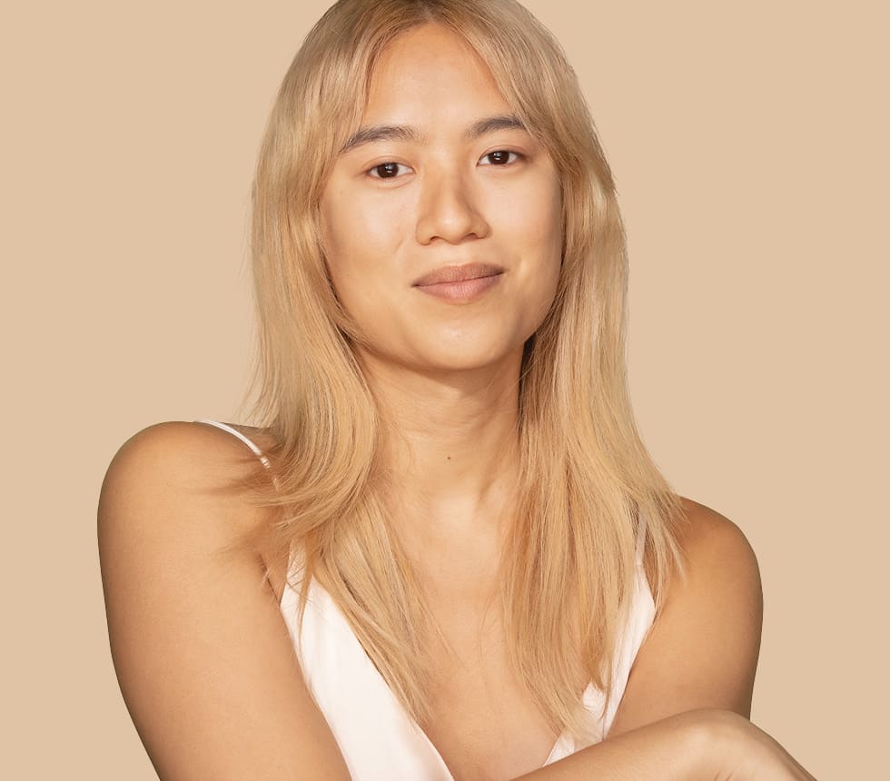 Woman with blond hair smiling against a beige backdrop